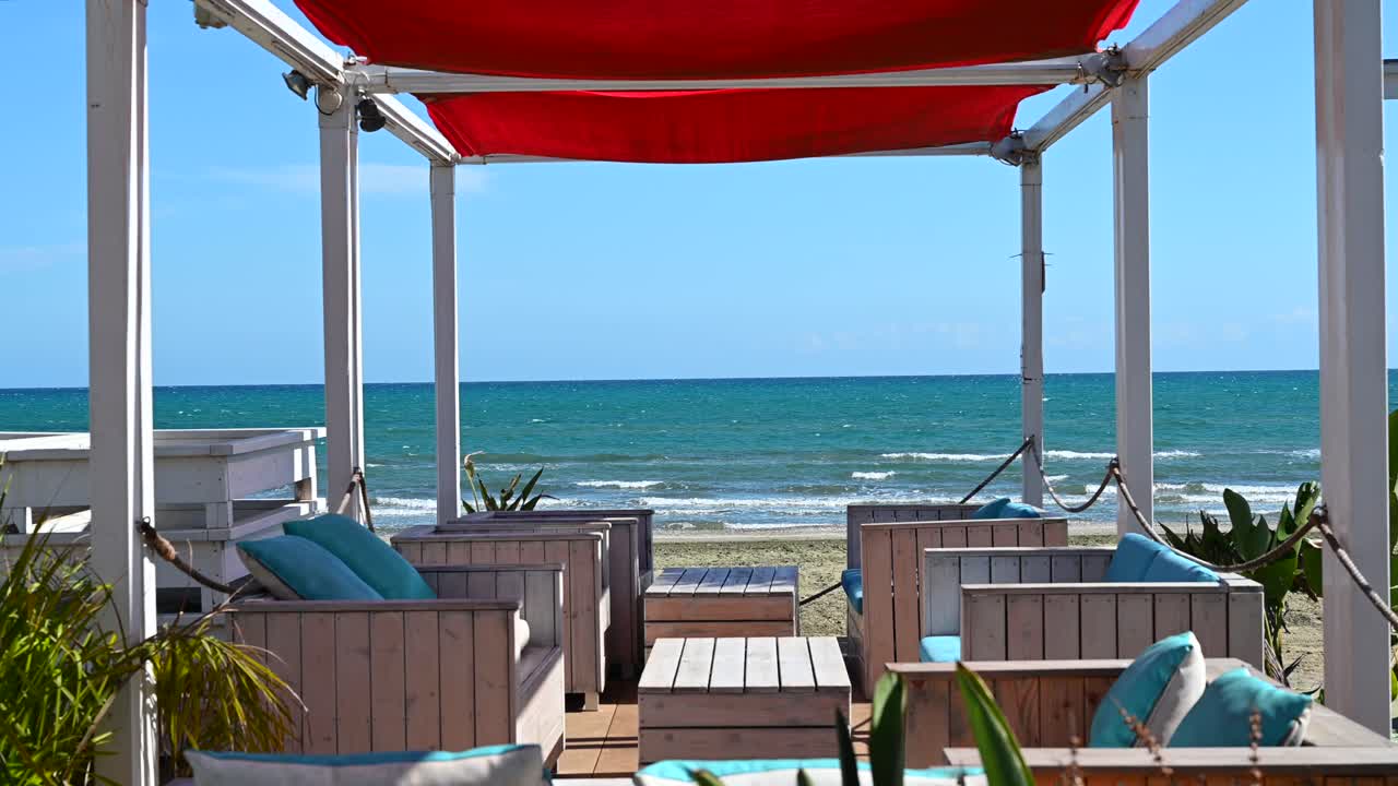 A seaside lounge shaded by a striking red canopy, overlooking the Mediterranean Sea in Larnaca, Cyprus