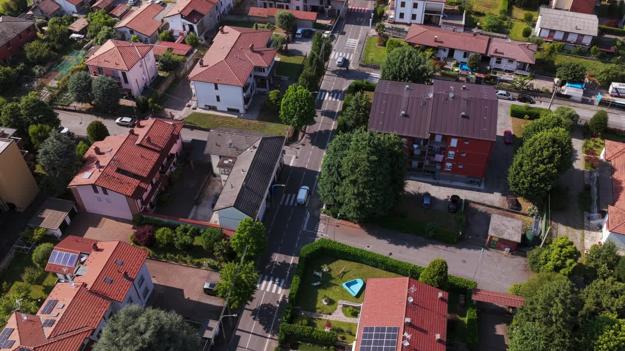 Drone capturing an urban landscape with residential buildings, streets, trees and solar panels, highlighting sustainable living and modern city life