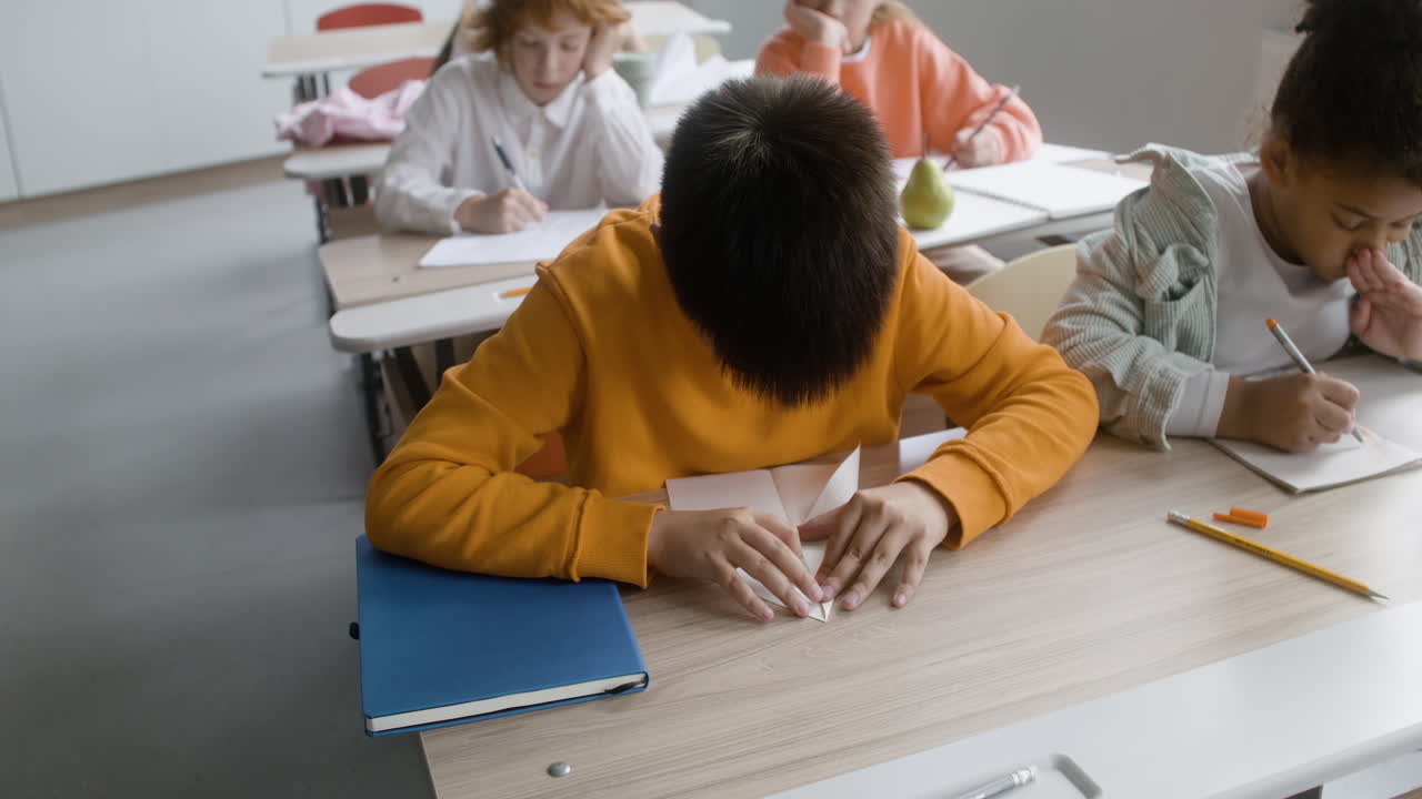 Kid doing paper airplane in the classroom.