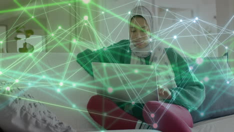 Animation-of-network-of-connections-over-biracial-woman-in-hijab-using-computer