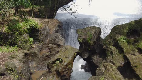 bandung waterfall : water flowing down an old historic river dam which was built by the dutch military around 17 ad, forming a waterfall rushing through canyon rocks in the jungle in bali, indonesia