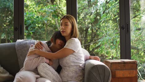 asian mother and daughter embracing and lying on couch