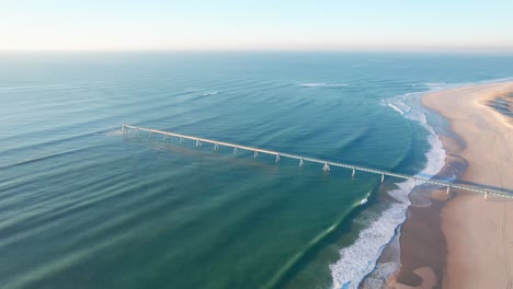 Beautiful-turquoise-blue-ocean-with-a-golden-sandy-beach-and-jetty