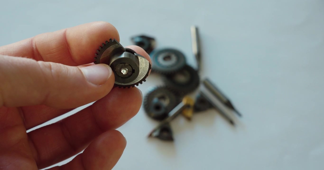 Primer plano de un inserto de carburo dañado sostenido en la mano, mostrando desgaste de la herramienta, filo de corte roto, mecanizado CNC, reparación y mantenimiento industrial