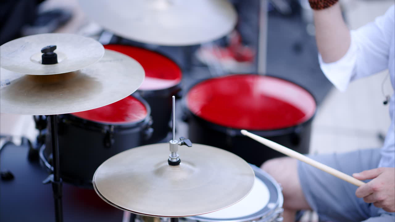 Close up of man playing red drums outside