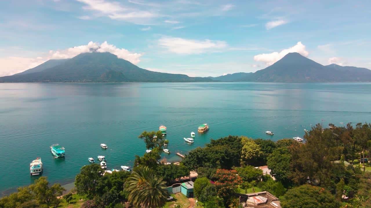 Droneflyvning over landsby, strand og både mod sø og vulkaner - Atitlán-søen, Panajachel, Guatemala - Sommer.