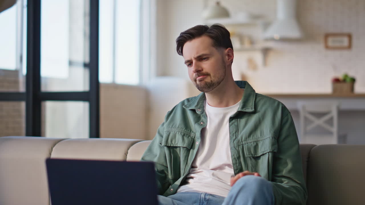 Sick man virtual chat using laptop at room sofa closeup. Serious guy coughing