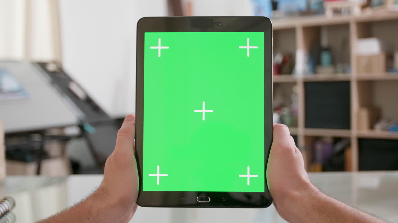 manos sosteniendo una tableta con una pantalla verde
