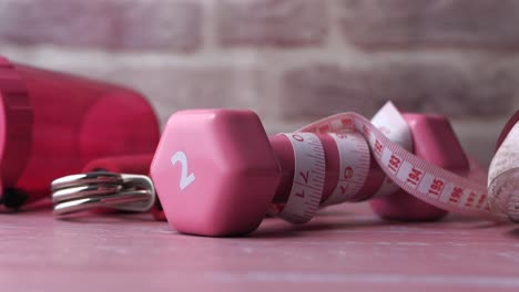 pink dumbbells and measuring tape for fitness