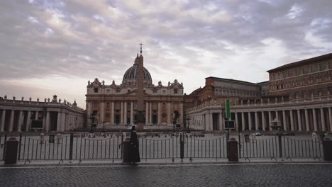 slow pan shot from right to left filming the vatican while a nun walks by in front of it in rome in 4k