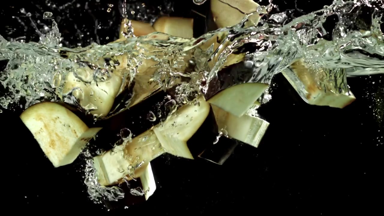 Fresh Chopped Eggplant Pieces Splashing into Water in Slow Motion