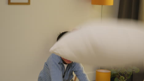 집에서 나게 행동하는 혼란스러운 어린 소년, 소파에 뛰어들고 라운지 1 주변에 베개를 던집니다.