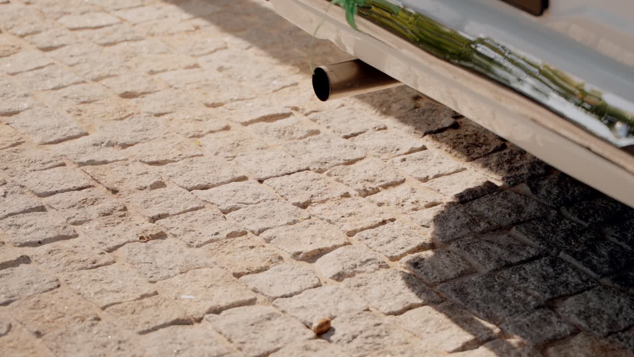 Close up of an old classic car exhaust pipe over cobblestone pavement
