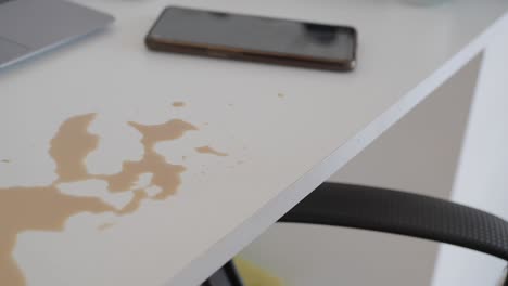 coffee spill on a white desk with laptop and smartphone