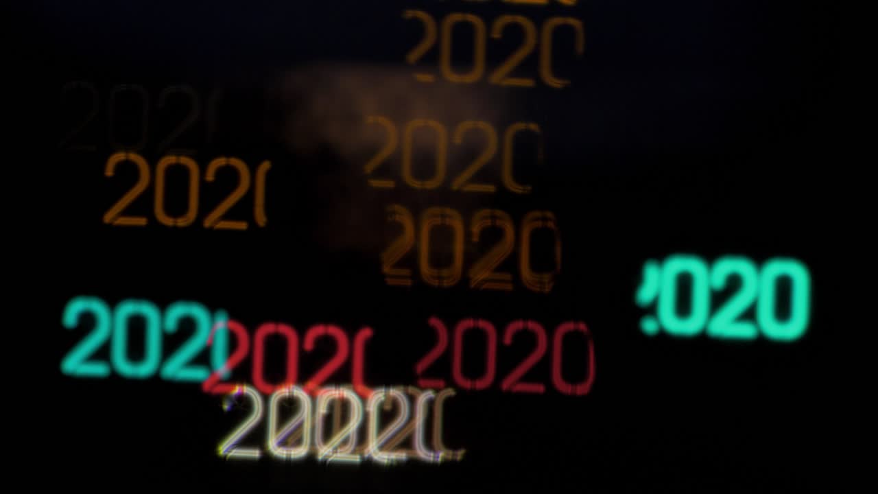 Bokeh colorato a forma dell'anno 2020 da auto in movimento e semafori di sera, sfondo a tema Capodanno o festività, spazio per il testo.