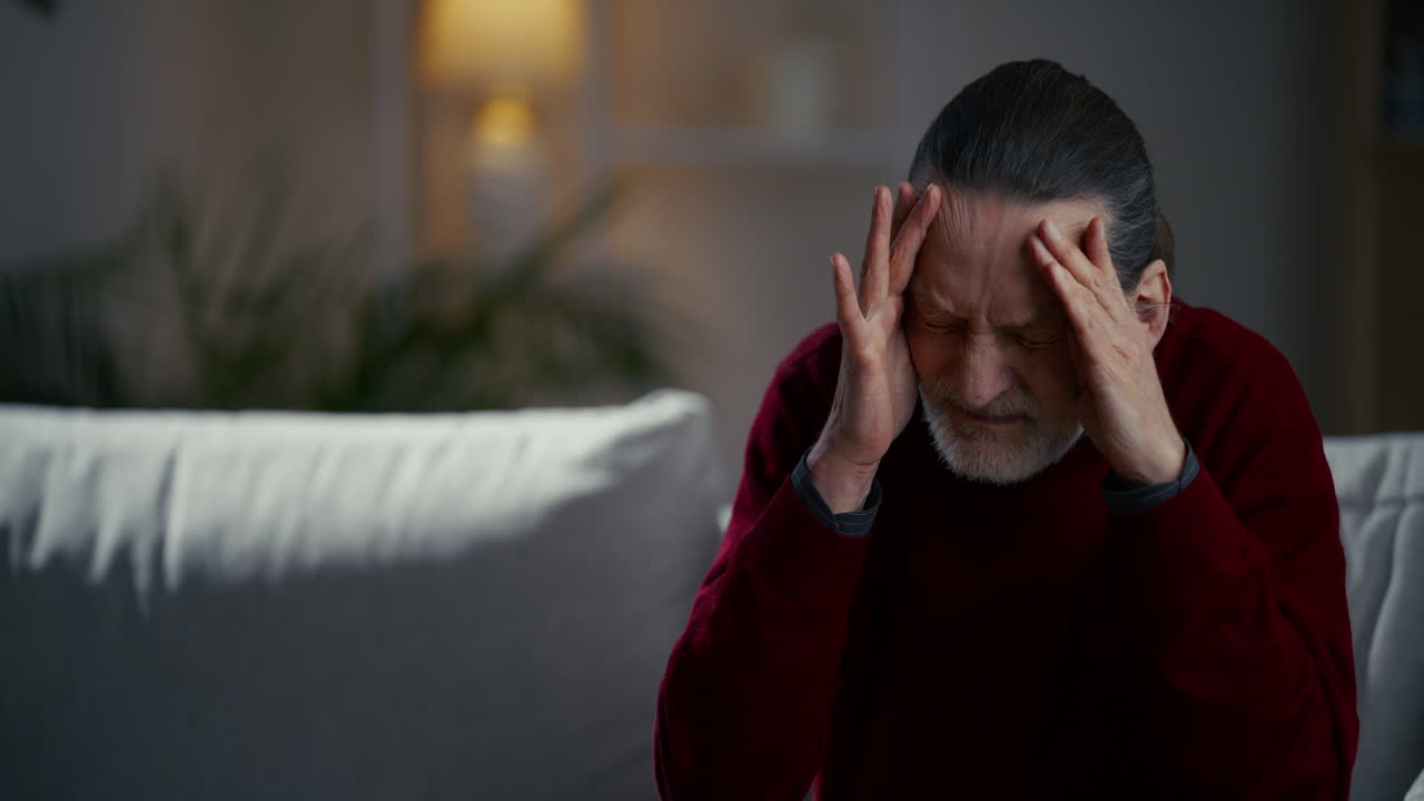 Elderly Man Suffering from Headache at Home