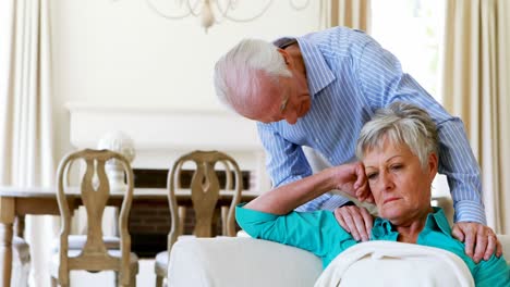 upset senior couple arguing with each other in living room