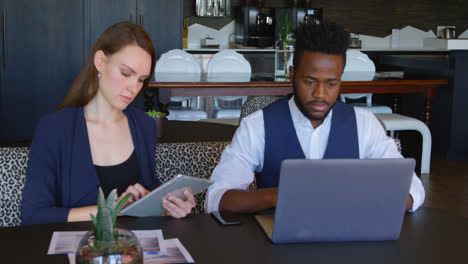 front view of young cool mixed-race business team working on multimedia devices in a modern office 4