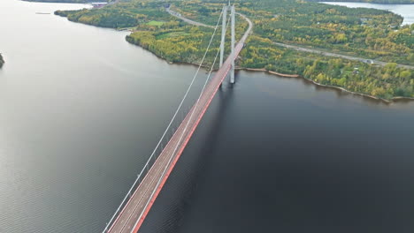 Vuelo-De-Regreso-Sobre-La-Vista-Panorámica-Del-Puente-Hogakustenbron-Con-El-Bosque-Otoñal-Al-Fondo-En-Suecia