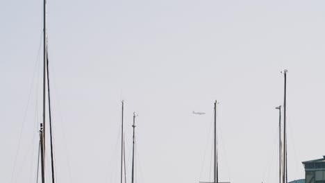 follow shot of an airplane getting ready to land at the airport with some boat masts in view