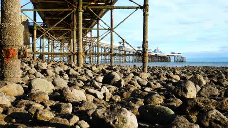 under weathered worn llandudno pier landmark support pillars at low tide dolly right shot