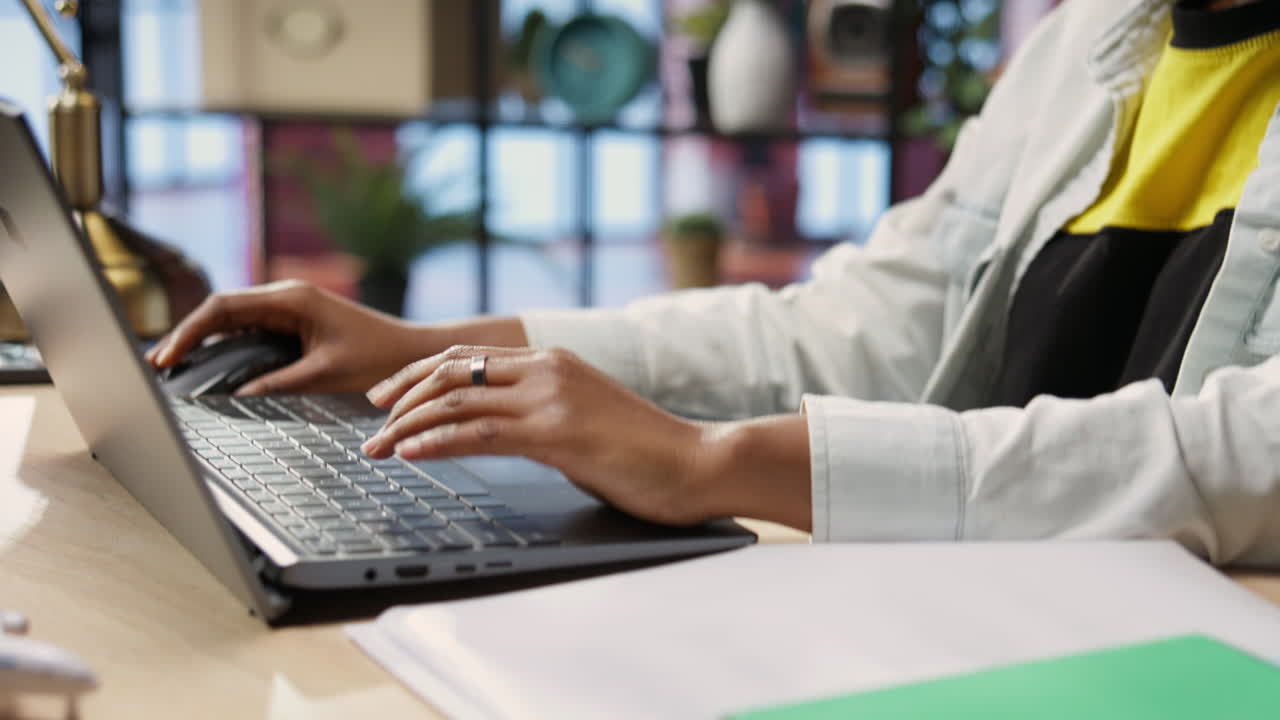 Teleworker typing on notebook keyboard in home office, close up