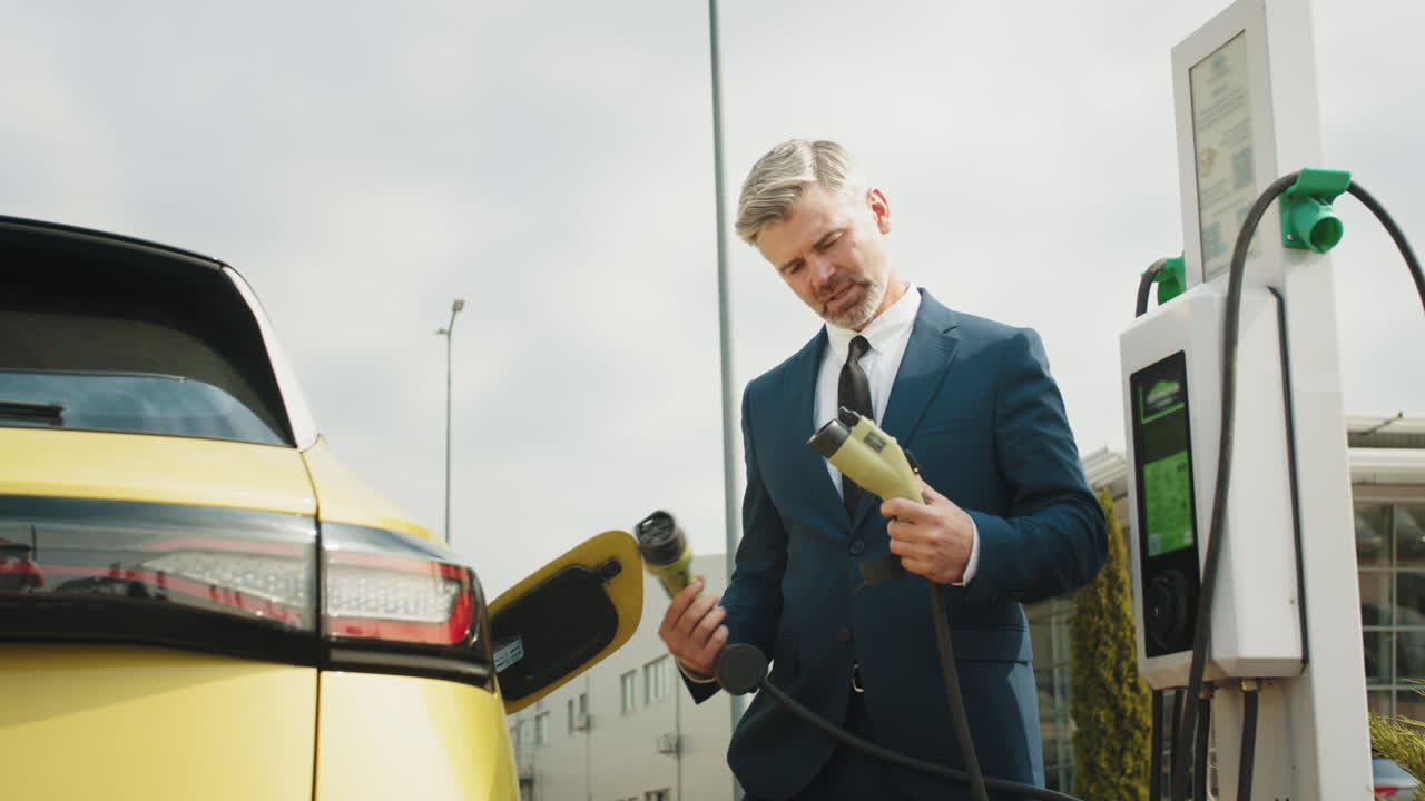 бизнесмен заряжает электрический автомобиль