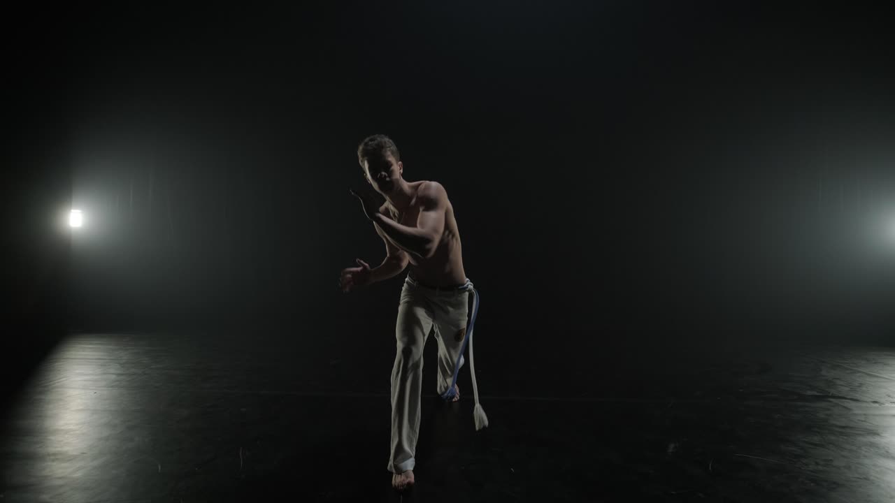 무대에서 역동적인 움직임을 보이는 카포에라 싸움, 무술, 춤, 액션 아크로바틱스, 스포트라이트 아래에서 힘, 유연성 및 기법을 보여주는 벌거벗은 가 운동선수