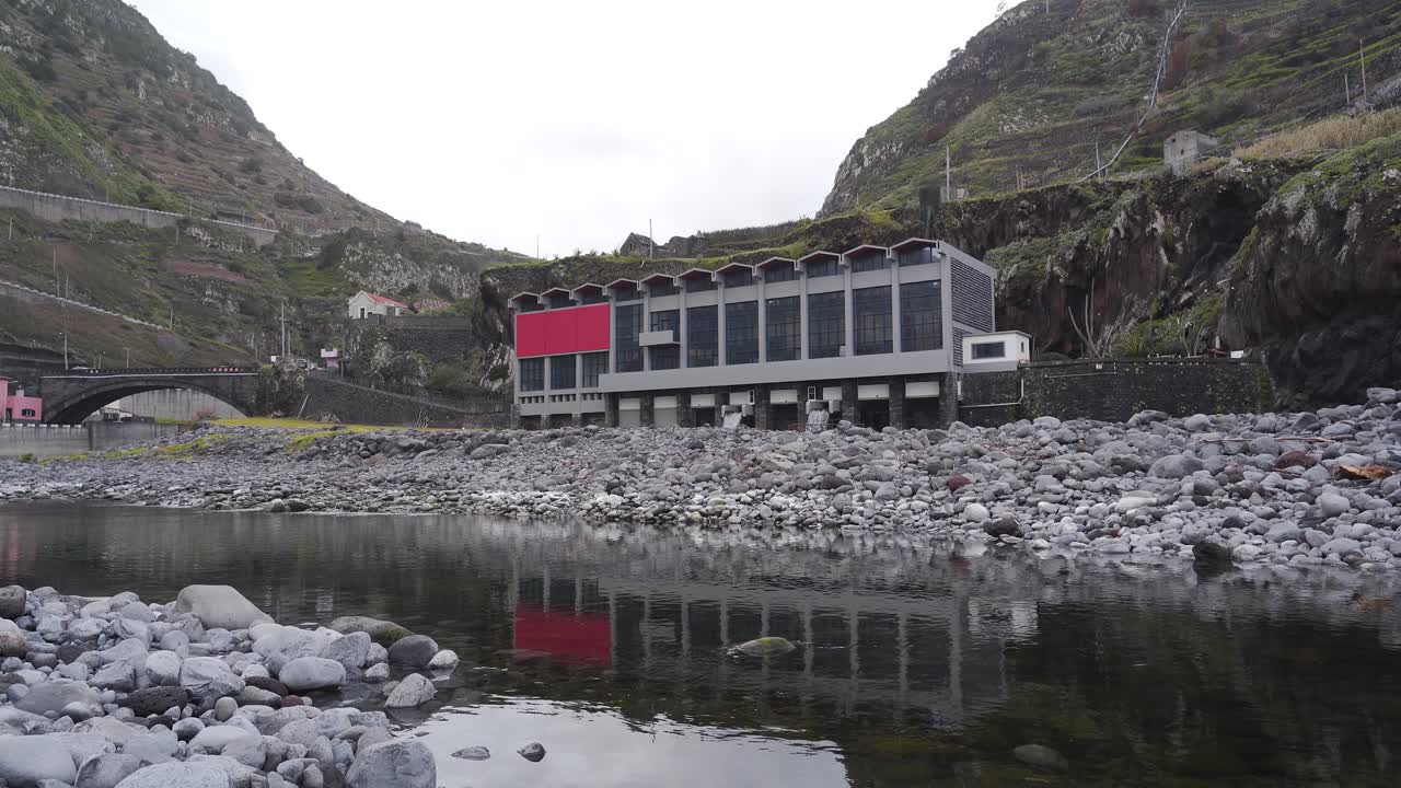 vista de una central hidroeléctrica en la desembocadura del río, cámara fija que muestra el agua saliendo de la central hidroeléctria de vuelta a la desemboca del río