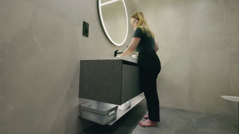 woman washing hands in modern bathroom