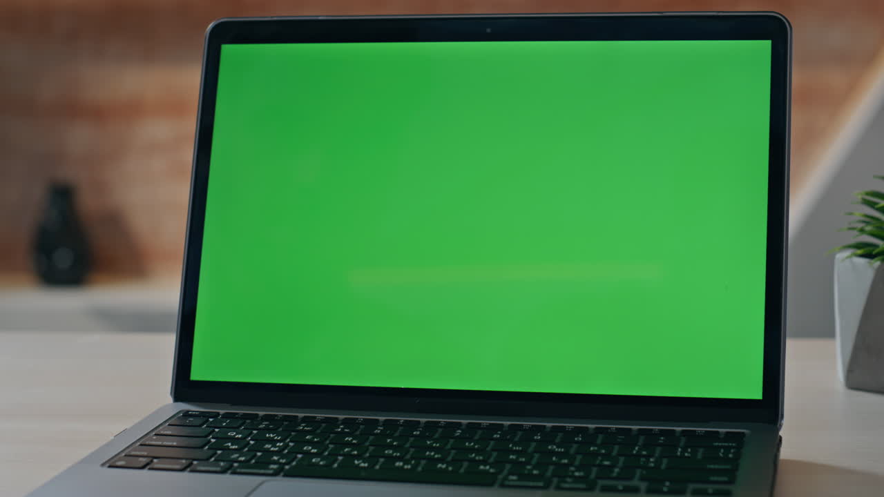 Empty chroma key laptop display on workplace desk closeup. Green screen computer