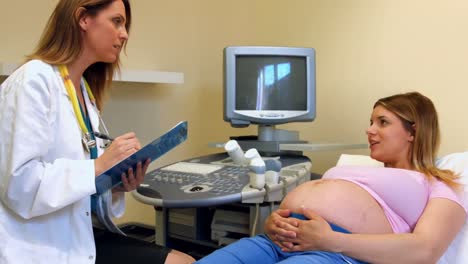 médico tomando notas de una paciente embarazada