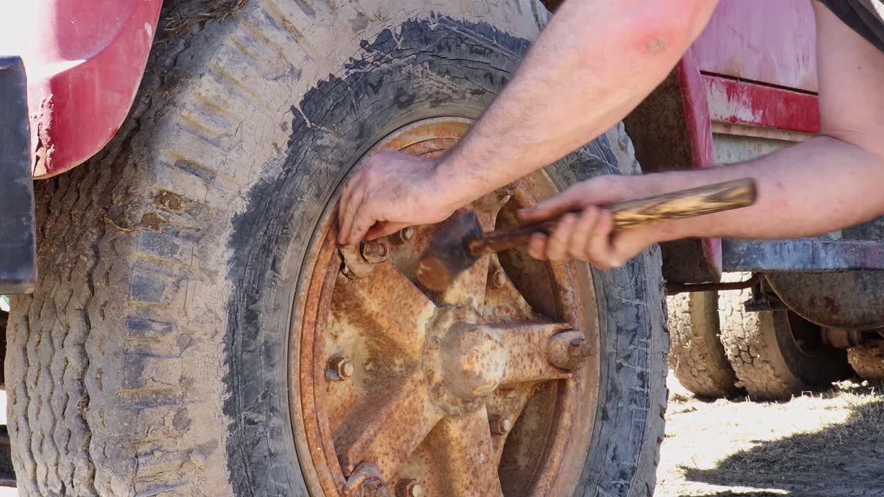 Knocking a rusted wedge block loose on a rusty Dayton rim in order to change wheels