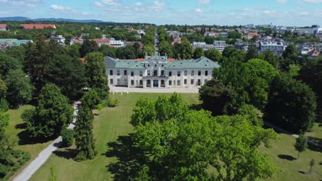 drone shot approaching an old palace surrounded by a green park