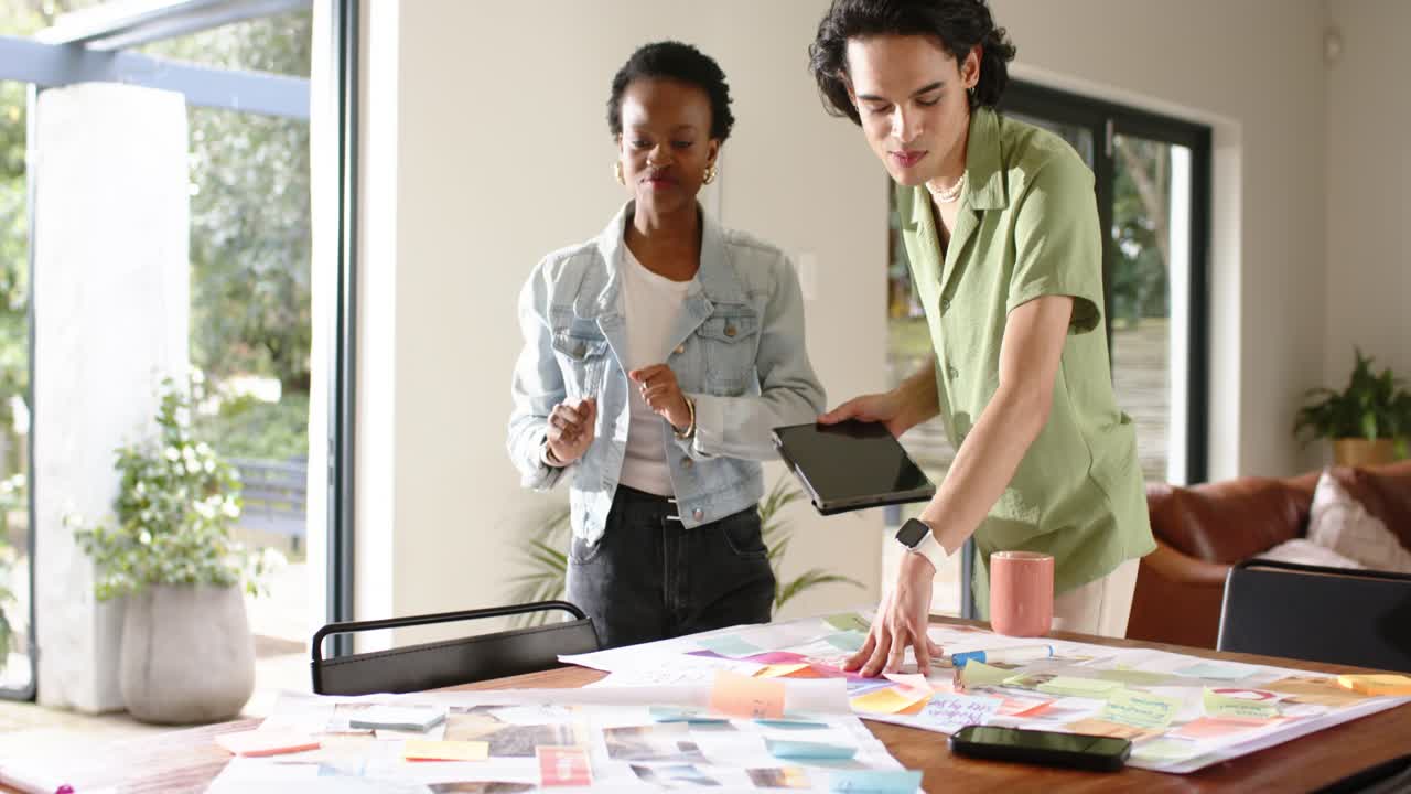 Reviewing tablet info, diverse team at home gesturing ideas, grouping charts, finalizing layout