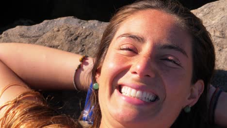 cheerful woman lying on the coastal rock - girl sunbathing at duranbah beach - new south wales, australia