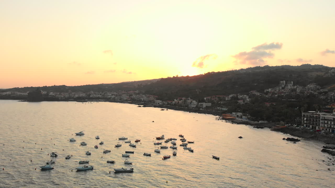 Aerial, boats moored in Mediterranean bay, sunset over mountains in background