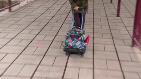 student pushing a backpack on a school campus