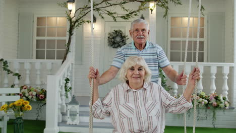 Pareja-De-Ancianos-Juntos-En-El-Patio-Delantero-De-Casa.-Hombre-Balanceándose-Y-Abrazando-A-Una-Mujer.-Familia-Madura-Feliz