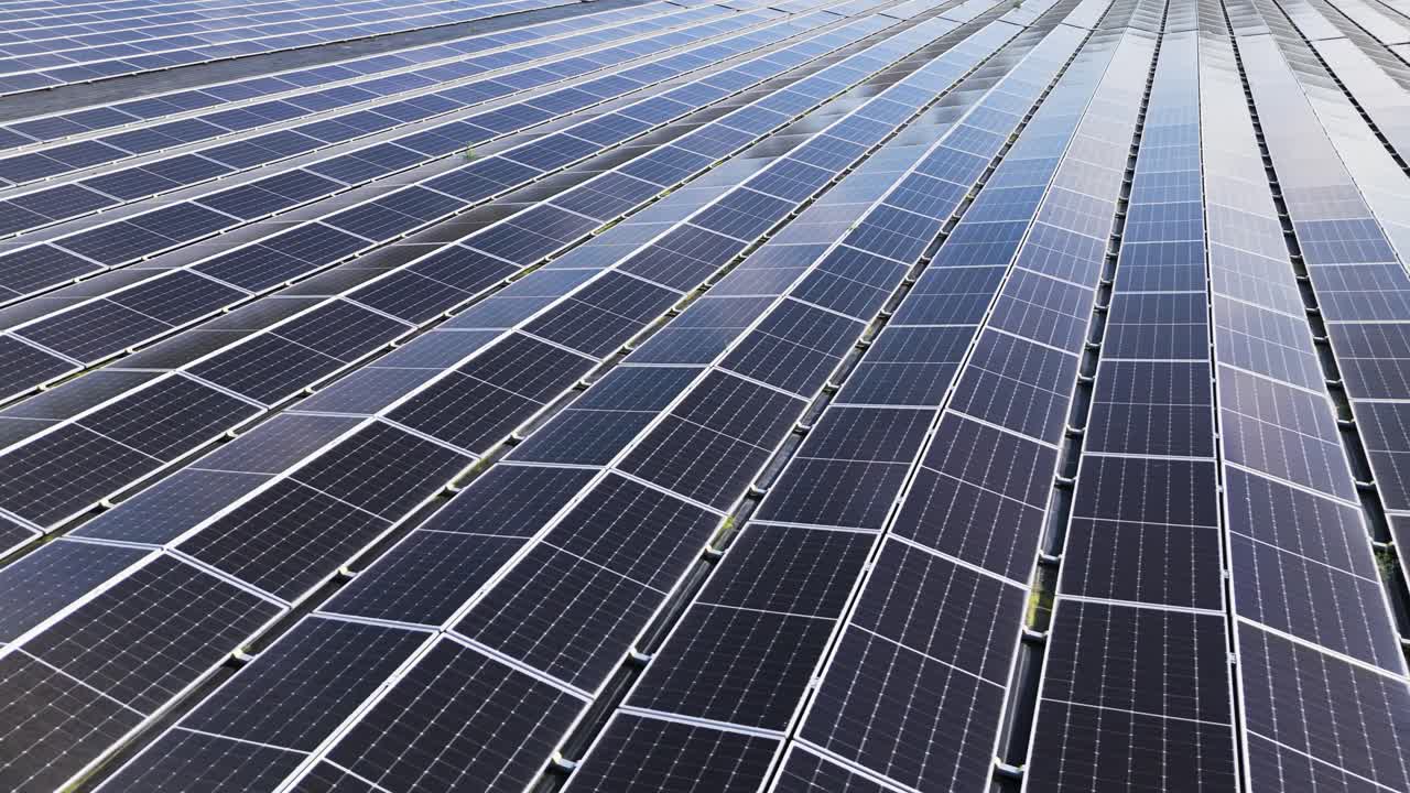 Filmato dettagliato con drone che mostra file di pannelli solari in una grande fattoria di energia rinnovabile che genera elettricità pulita