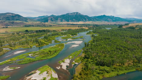aerial view of a winding river through a forested valley with mountains