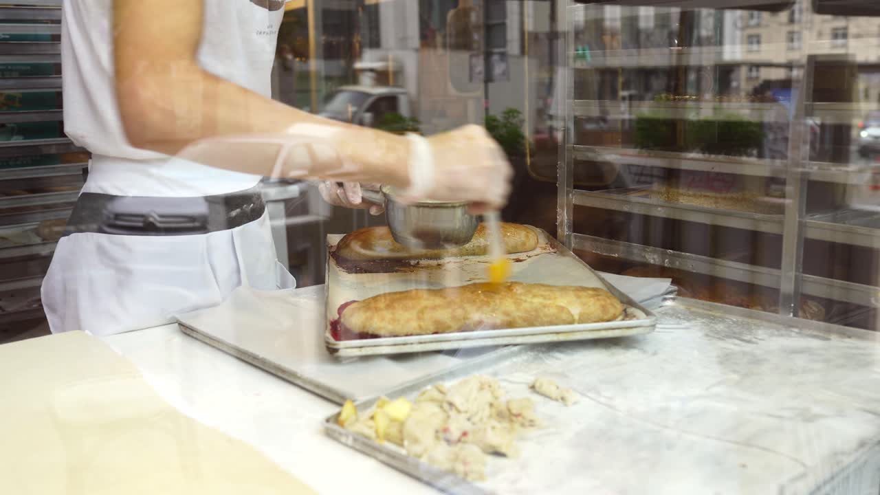 panadero preparando y esmaltando pasteles de strudel en una panadería