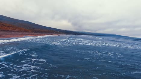 un día nublado sobre la playa de fanore en irlanda, con olas que chocan contra una costa serena