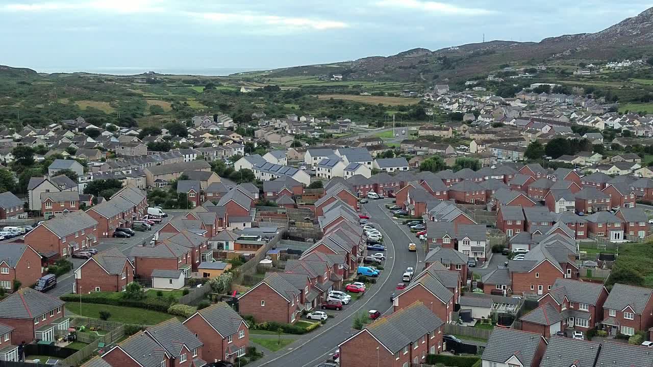 North Wales red brick modern housing neighbourhood under Holyhead mountain aerial view overhead