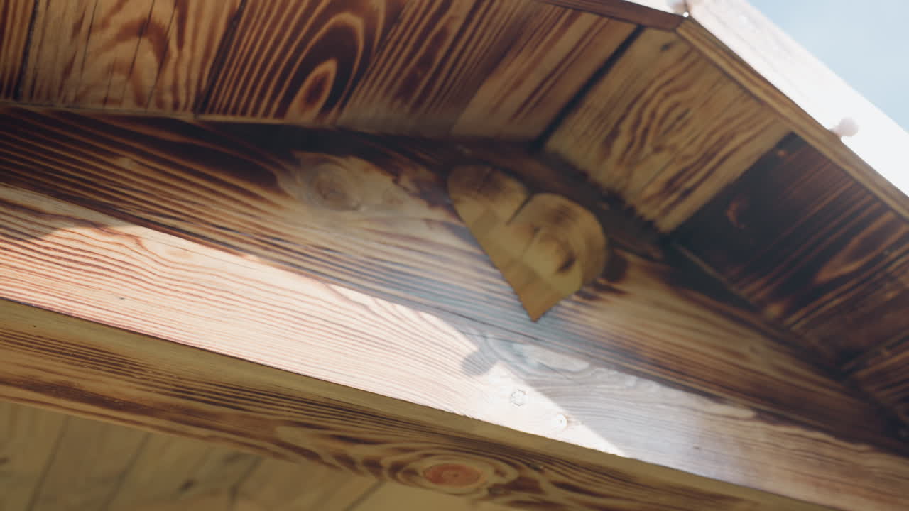 Heart shaped cutout on wooden building gable illuminated by sunlight showcasing wood grain patterns and rustic craftsmanship detail with visible nail accents