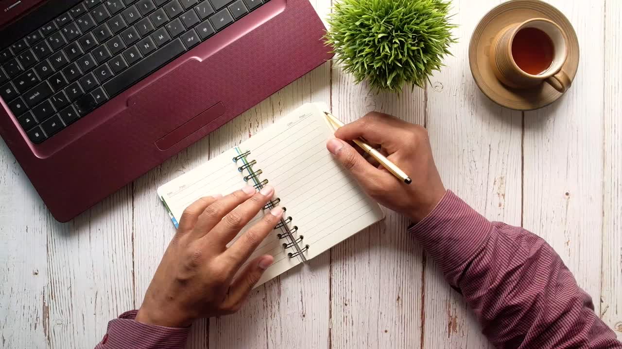 Person working at a desk with laptop and notebook