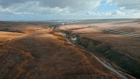 Aerial-drone,-cinematic-footage-of-a-country-winding-road-on-Saddleworth-Moor,-Greater-Manchester,-UK