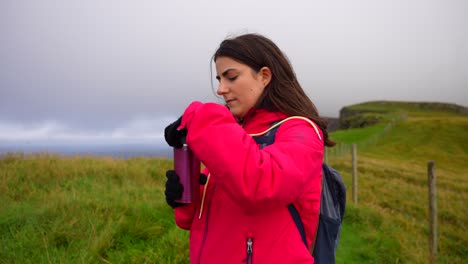 Nahaufnahme-Einer-Jungen-Frau-Auf-Einer-Wanderung,-Die-Heiße-Getränke-In-Der-Landschaft-Der-Färöer-Inseln-Trinkt