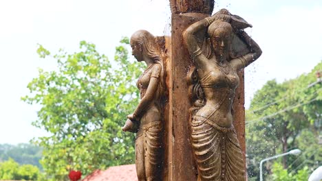 estatua con fuente de agua en medio de vegetación exuberante