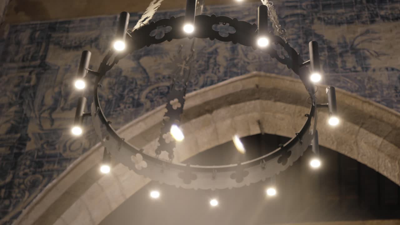 Elegant chandelier glowing softly against traditional blue tile wall in dim light